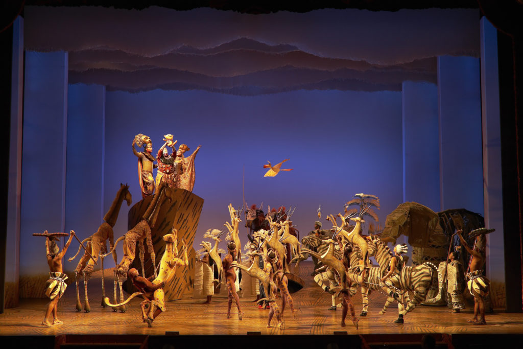 Animals are onstage below Pride Rock in the Circle of Life. 