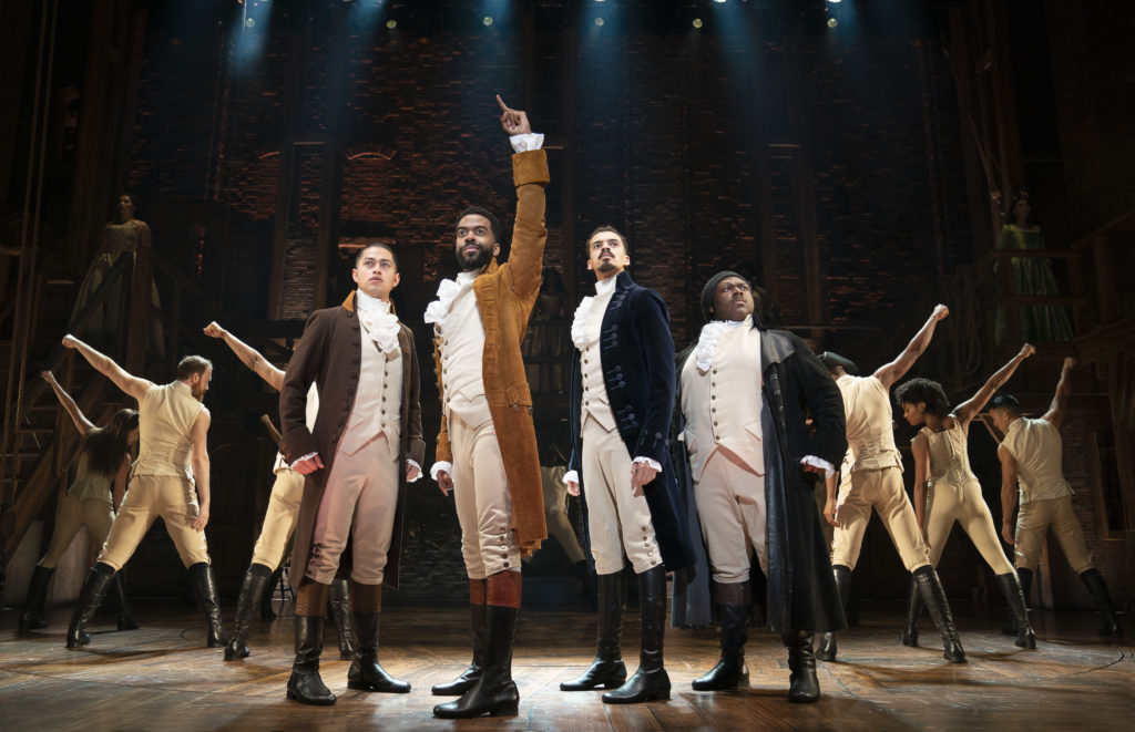 The company of Hamilton looks out in a star-like pose towards the audience.