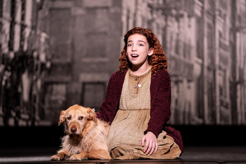 Red-headed Annie and her dog Sandy are onstage as Annie sings.