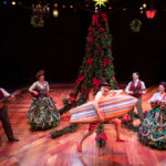 Cast sings onstage before a Christmas tree. Ebenezer is in his bathing suit with a surfboard.