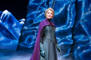 Elsa smiles midstage with an icy lanscape behind her.