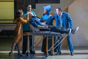 The cast gathers around Sebastian, who lies on a hospital bed.